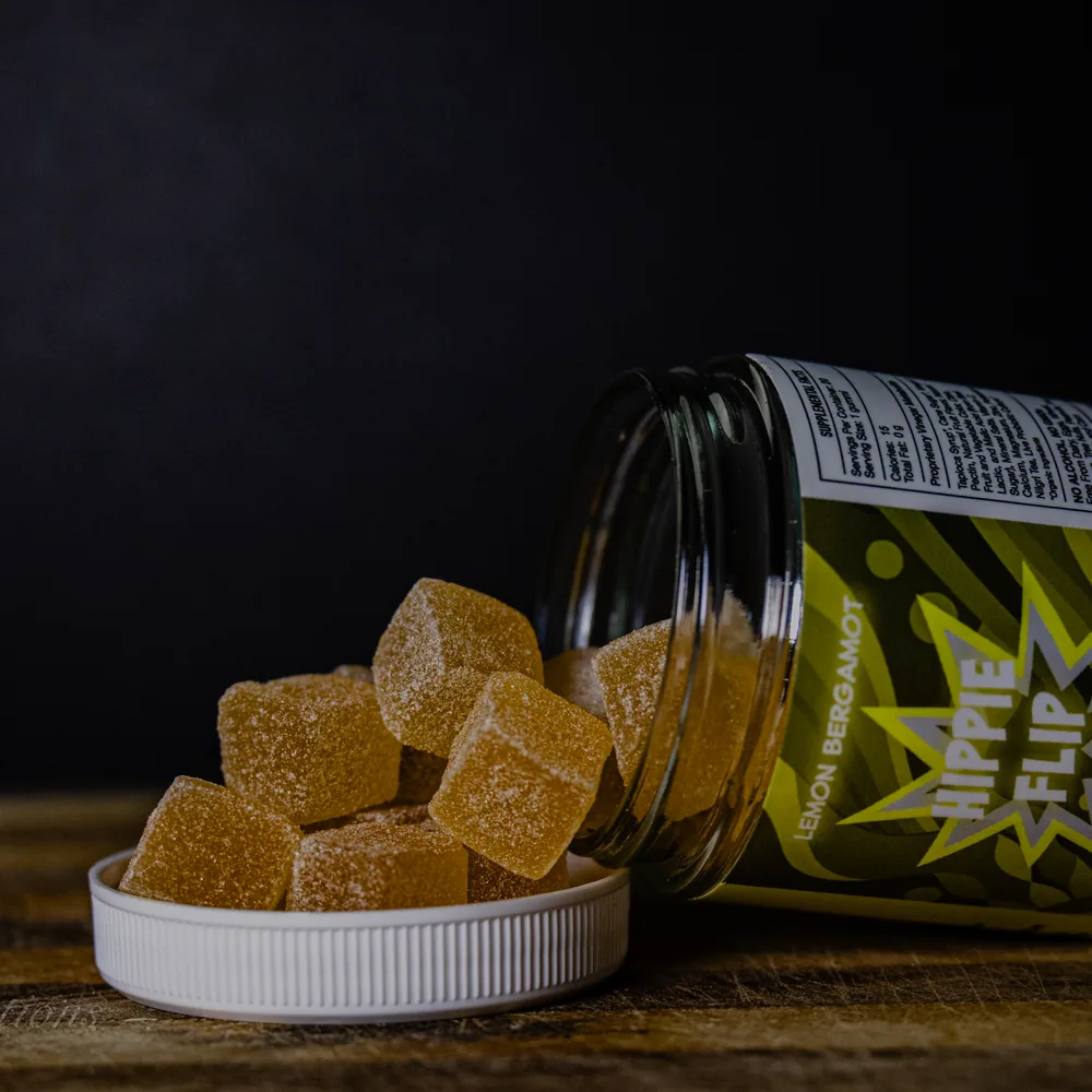 BAMM Hippie Flip glass jar with lemon bergamot gummies on a dark studio backdrop.