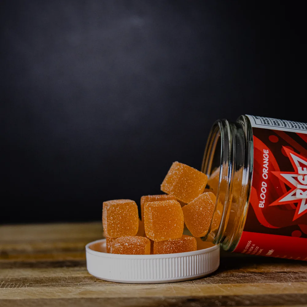 BAMM Rise Up glass jar with orange gummies on a dark studio backdrop.