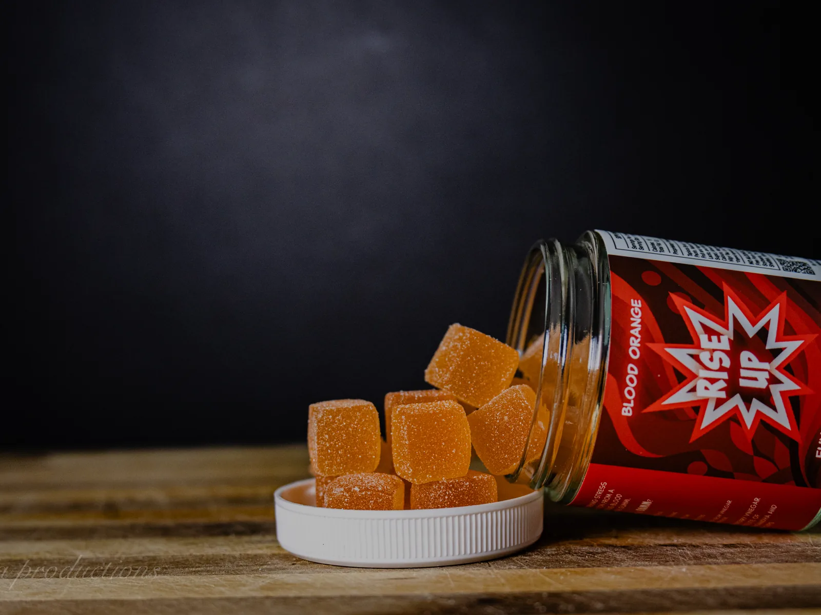 BAMM Rise Up glass jar with orange gummies on a dark studio backdrop.