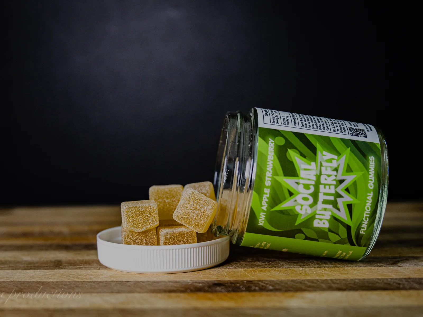 BAMM Social Butterfly glass jar with kiwi apple strawberry gummies on a dark studio backdrop.